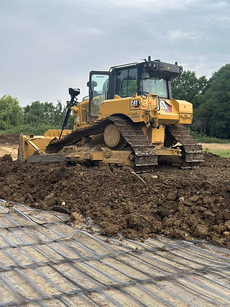 A yellow bulldozer pushes earth on a construction site