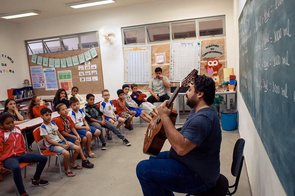 Professor toca violão para alunos em escolas participantes do Violão na Escola.