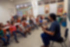 Professor toca violão para crianças em sala de aula da Galeria.