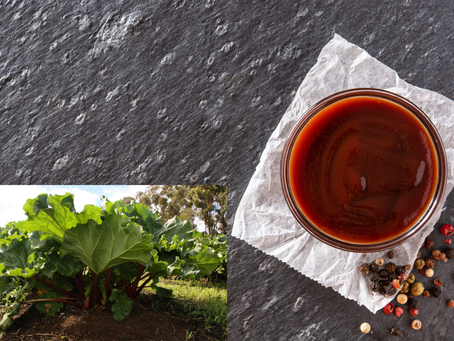 Bowl of Tomato & Rhubarb Sauce on parchment with colorful peppercorns. Inset of lush green rhubarb plants in a field, blue sky above.