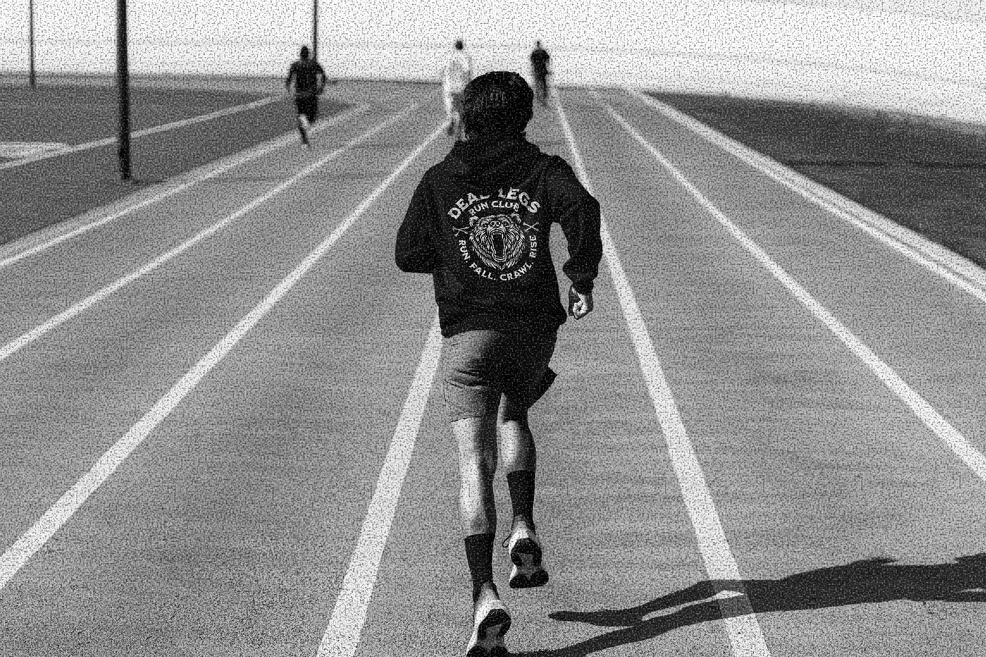Club member warming up on the track wearing a Dead Legs Run Club hoodie, part of a custom apparel branding project by Overland Design Co, a Las Vegas design studio.
