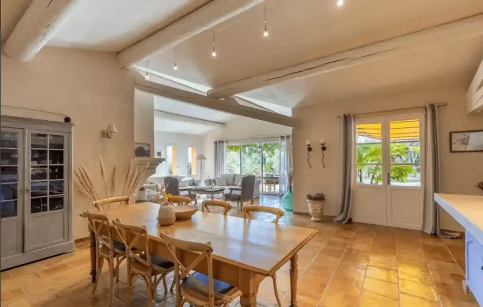 Salle à manger lumineuse avec une grande table en bois, LA MAISON et vue jardin.