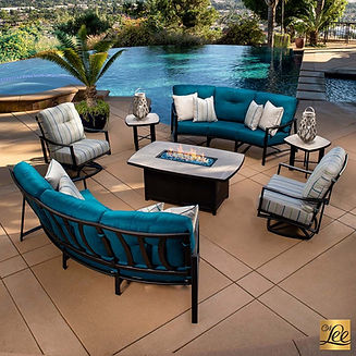 Modern outdoor patio set with deep blue cushions, a rectangular fire pit table, and poolside placement, showcasing Emigh's new collection.