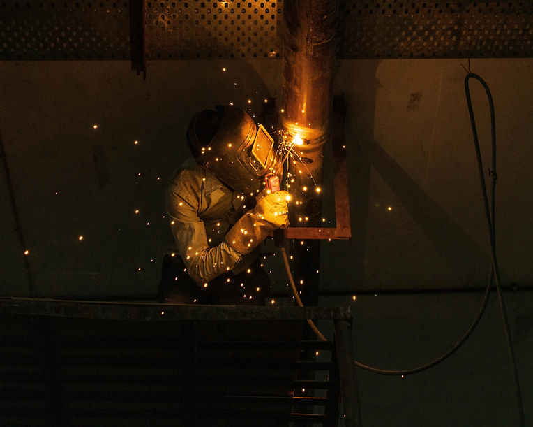 Welder working with sparks flying during field welding