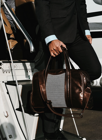 a man stepping off a private jet with a walter leather travel bag