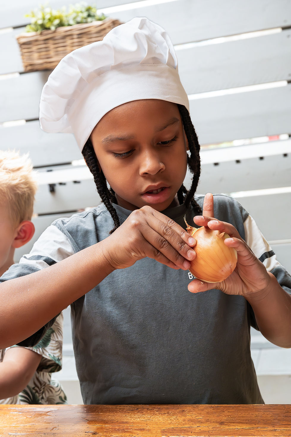Kind pelt een ui bij kookles KooKjes Rheden