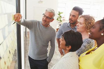 A man explains a point on a display to a diverse group of colleagues.