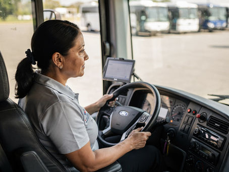 A female driver steers a van through a parking lot.