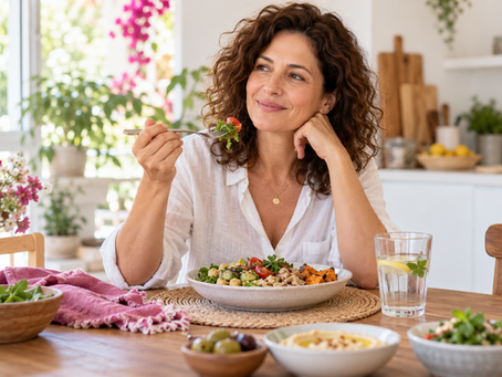 אישה בוגרת יושבת בנחת ליד ארוחה מגוונת וכוס מים בבית מואר.