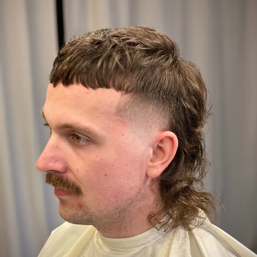 Modern mullet with textured fringe and fade on the sides, side profile