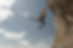 Climber hanging by one hand from a cliff edge, symbolizing high-stakes decision making and the urgency of strategy-first cybersecurity.