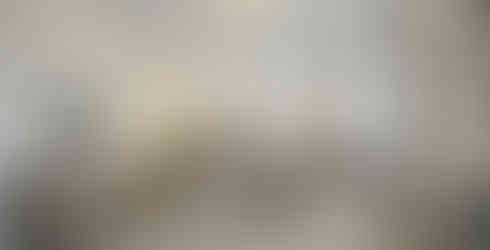 Virtual staging of a large primary bedroom with an upholstered bed, neutral layered bedding, matching wood nightstands, warm lighting, and soft drapery in a modern transitional design.