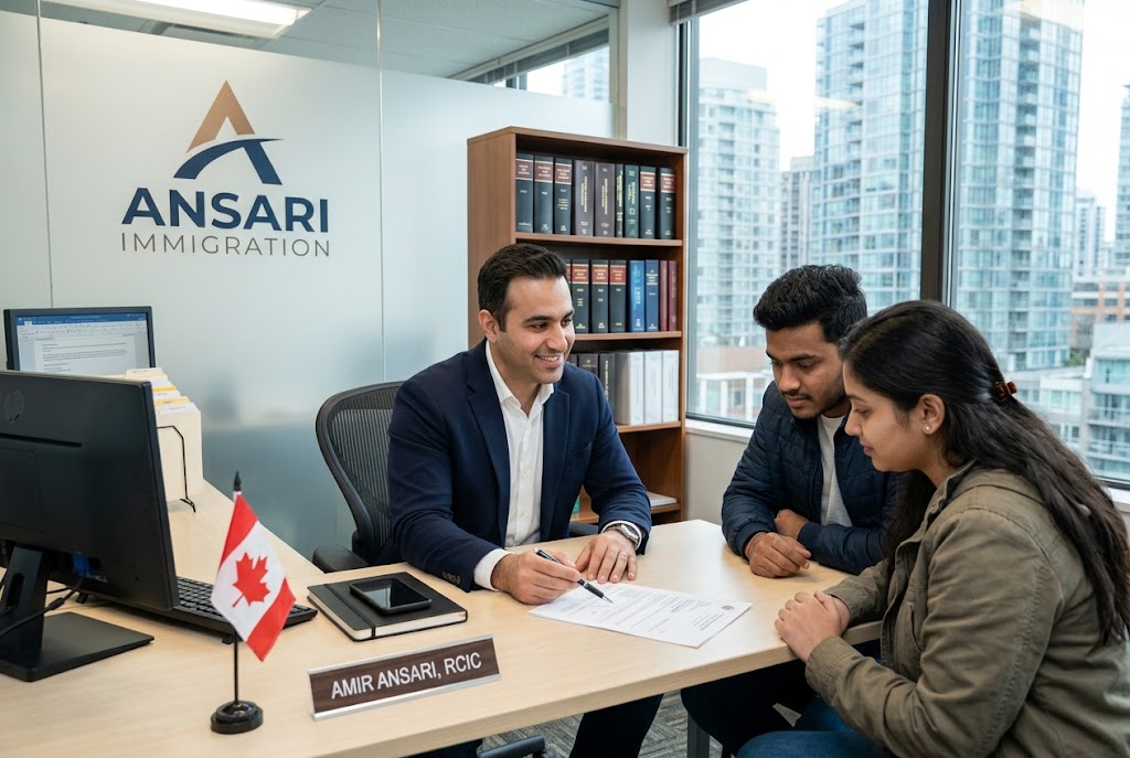 Amir Ansari, a licensed Regulated Canadian Immigration Consultant (RCIC) at Ansari Immigration, sits at his office desk in Vancouver, BC, guiding a young South Asian couple through their application process. He is pointing to a document on the table while the couple listens attentively. The office features a glass partition with the "ANSARI IMMIGRATION" logo, a small Canadian flag on the desk, a nameplate reading "AMIR ANSARI, RCIC", and a bookshelf in the background with city views visible through the window.