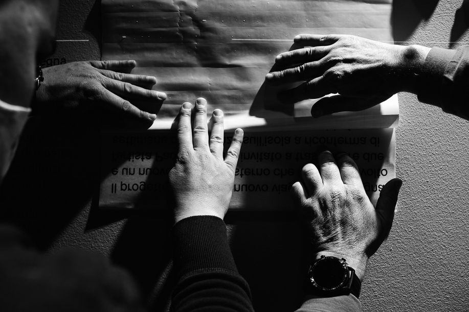 Fotografia di mani che lavorano all'allestimento di una mostra.