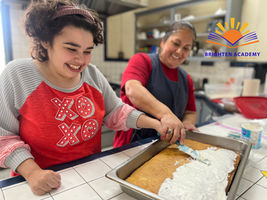 Young women learning how to ice a cake