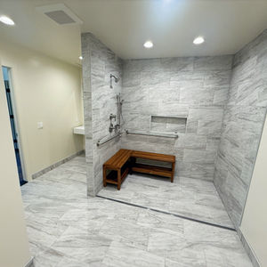 A completed bathroom remodel, featuring a walk-in shower with a line drain and two-bathroom stalls. 