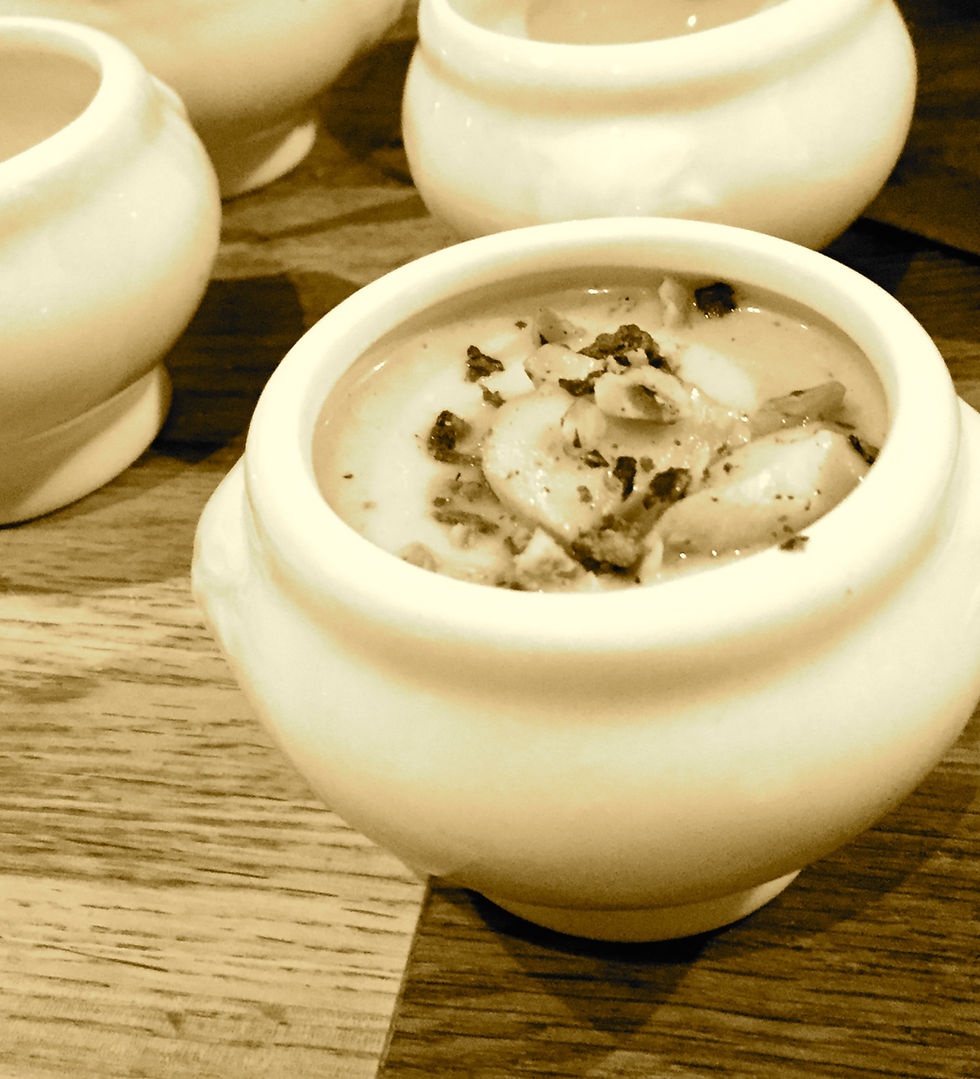 Pot de soupe crèmeux garni de champignons sur une table en bois, ambiance chaleureuse et apaisante. Quatre pots visibles.