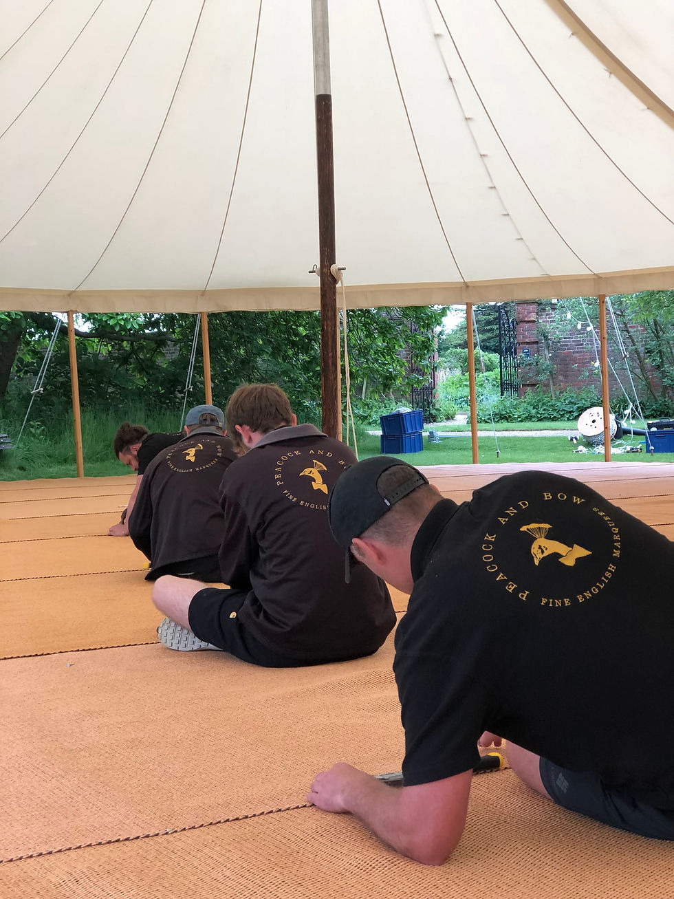 The Peacock and Bow crew lay the flooring inside a pole and canvas marquee.