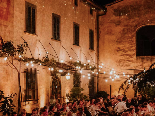 A courtyard wedding feast under festoon lights at the Castello del Monsignore in Tuscany.