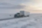 pickup towing an enclosed cargo trailer on a snowy prairie highway