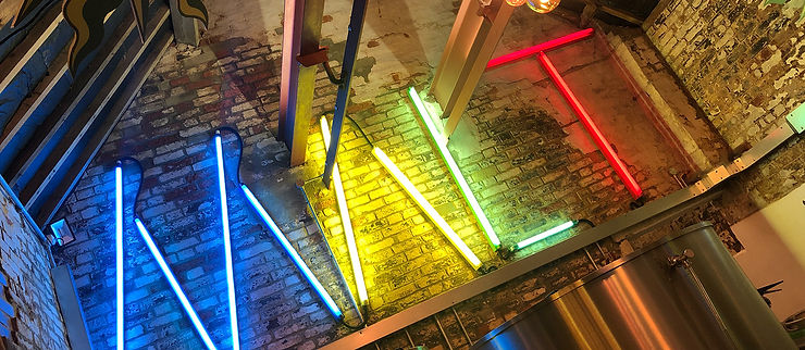 Neon sign against a brick wall spelling the word Malt