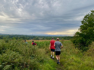 Runners on a trail run through a green field