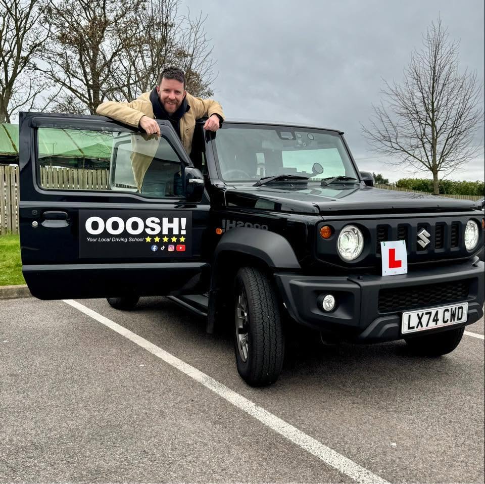 Jamie Traynor, founder of DriveBox, leaning on his OOOSH! driving school car