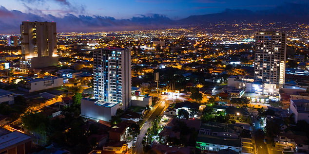 Night view of buildings in a city with lights Expat Senior Concierge CR.