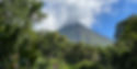 Volcano peak obscured by clouds, lush green jungle with mountain backdrop, Costa Rica.