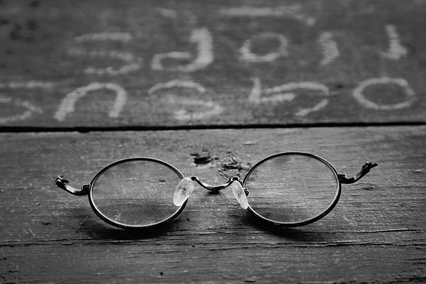 broken wire rim glasses on graffitied wo