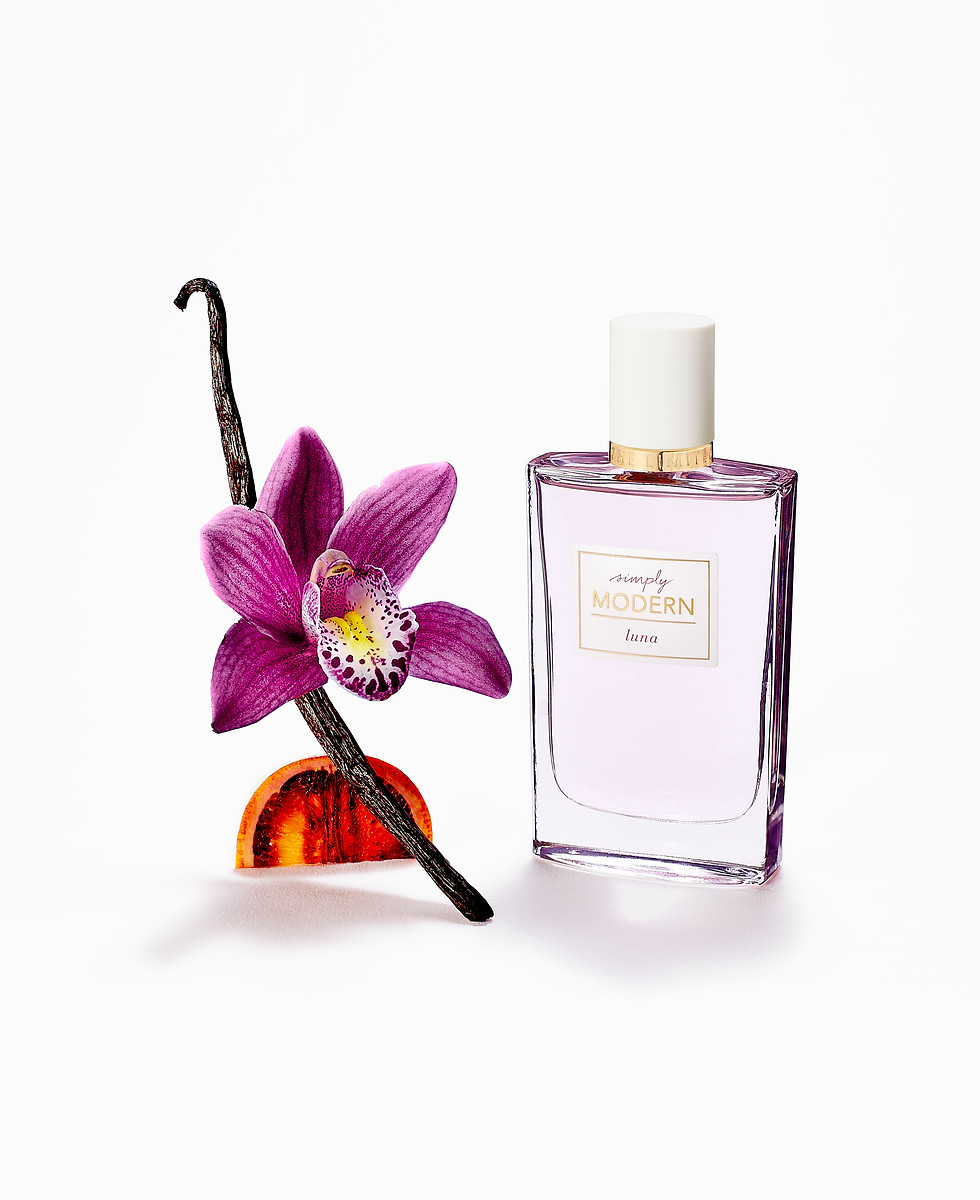 Minimalistic sculpture of fragrance notes, vanilla stick, blood orange, and violet orchid, beside a bottle with lilac liquid