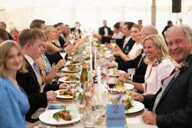 Guests at a long table, dining and toasting