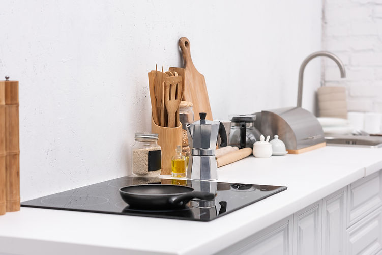 Clean frying pans on stove at modern kitchen with various utensils