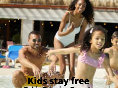 WestJet Vacations ad shows a family splashing in a resort pool; text reads Kids stay free Bahia Principe Resorts.