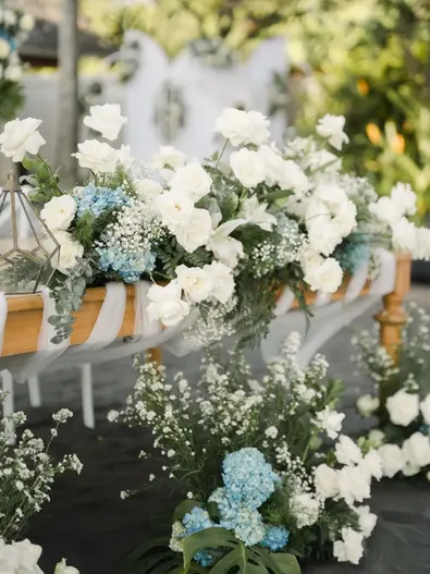 Close-up of aisle wedding floral decorations with white roses and light blue accents.