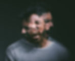Blurred motion image of a person with multiple overlapping faces showing distress and yelling, wearing a gray sweater against a dark background.