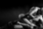 A black and white image of an intimate embrace between a couple on a dark background, conveying a passionate and romantic mood.