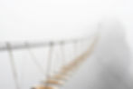 Fuzzy man walking on hanging bridge vanishing in fog. Focus on middle of bridge. .jpg