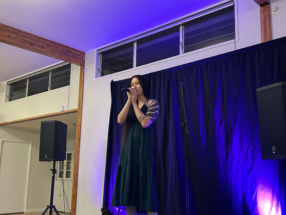 Performer in green dress holding microphone and singing. 