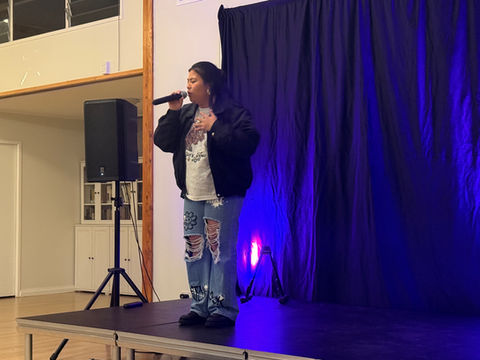 Performer singing into a microphone on stage. 