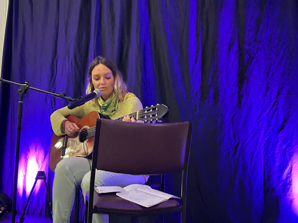 Performer is singing and playing acoustic guitar 