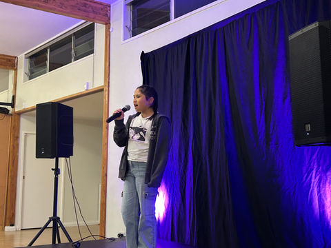 Young performer singing into a microphone on stage. 