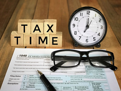 Tax-filling concept - ‘Tax time’ words on wooden blocks, pen, eyeglasses, featuring half o