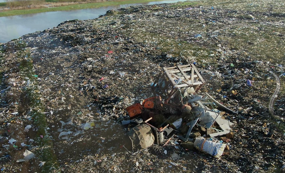 Large rural site filled with rubbish, including wooden crates, general waste and plastic. The area is polluted with fly tipping.