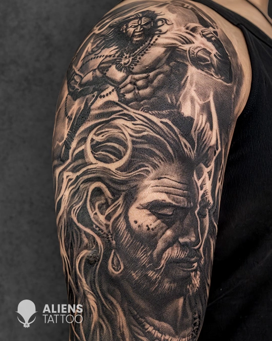 Detailed black and grey warrior portrait tattoo with intense facial expression and muscular figure, expertly inked by Aliens Tattoo, known as the best tattoo studio in pune.