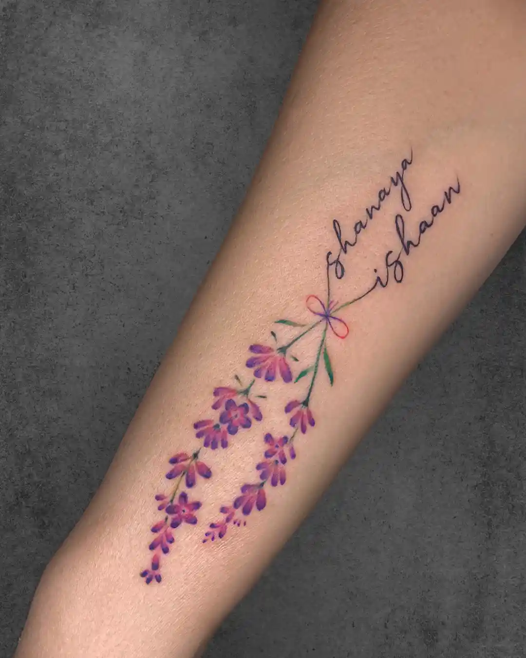 Delicate floral tattoo on a woman's forearm with names "Shanaya" and "Ishaan," representing love for her children or family members.