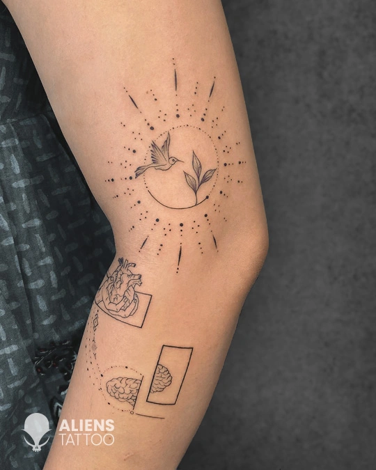 Minimalist line art tattoo featuring a flying bird, geometric circle, and abstract symbols on the arm, created by Aliens Tattoo, the best tattoo studio in pune.