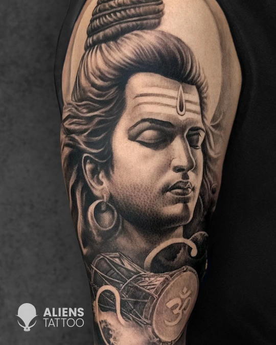 Hyper detailed Lord Shiva tattoo in black and grey with calm meditative expression and Om symbol, expertly inked by Aliens Tattoo, the best tattoo studio in pune.