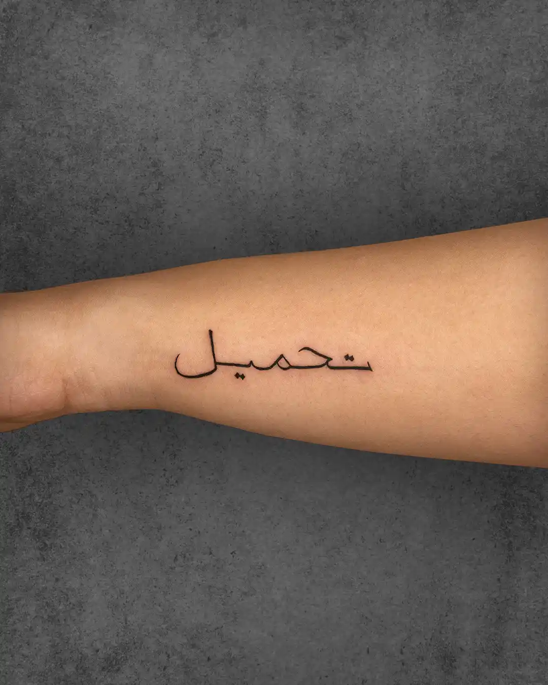 Arabic script tattoo on a woman’s forearm, conveying personal meaning or a powerful message in a clean, minimalist design.