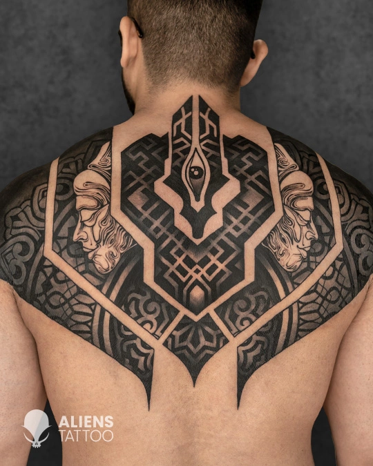Large symmetrical geometric back tattoo with bold blackwork patterns and detailed line symmetry, covering upper back and shoulders, created by Aliens Tattoo, the best tattoo studio in pune.